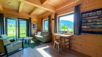 Ein gemütliches Blockhaus-Interieur mit Holzwänden, einer Couch, einem Tisch und einem Bücherregal.