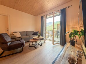Sala de estar com sofá, poltrona, mesa de centro e varanda com vista.