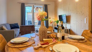 A dining table set with plates, wine glasses, and a vase of flowers. - Cosy apartment near ski area Nassfeld (Rattendorf)