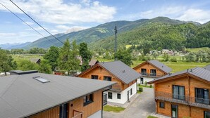 A row of wooden cabins with a mountain backdrop, a clear sky, and a power line. - Cosy apartment near ski area Nassfeld (Rattendorf)