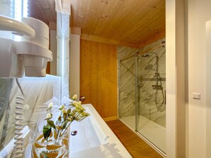 Ein modernes Badezimmer mit Duschkabine aus Glas, einer weißen Badewanne und einer Glasvase mit Blumen.