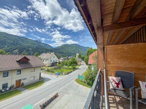 Ein Balkon mit Blick auf eine Straße, Häuser und Berge.