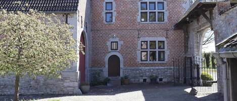 Un edificio histórico con fachada de ladrillo, múltiples ventanas y un patio empedrado.