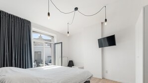 Een moderne slaapkamer met een groot bed, een aan de muur bevestigde televisie en uitzicht door een schuifdeur.