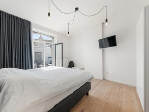 Un dormitorio moderno con una cama grande, un televisor montado en la pared y vistas al exterior.