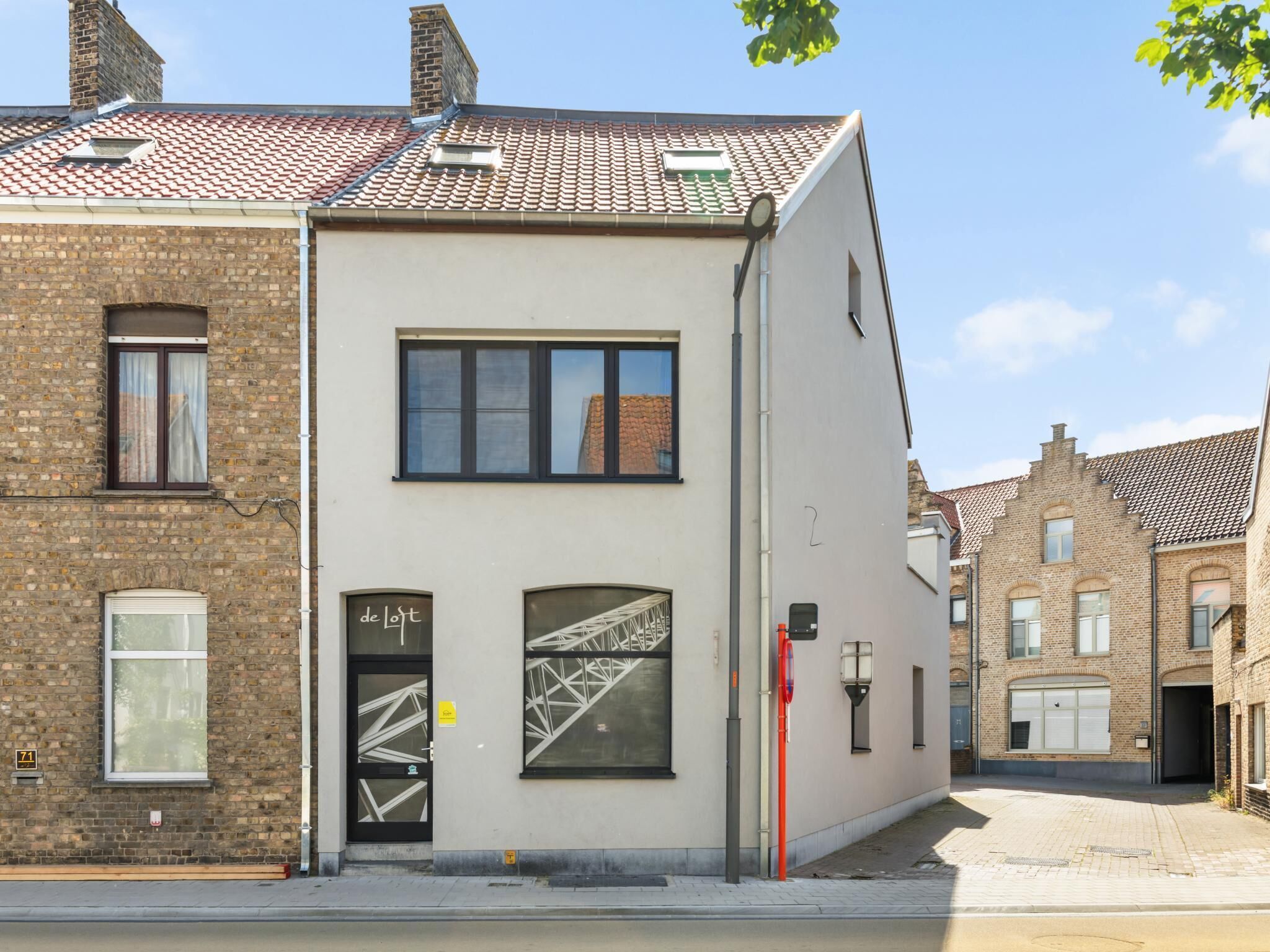 A two-story building with a brick facade, a flat roof, and a modern entrance with a glass door.