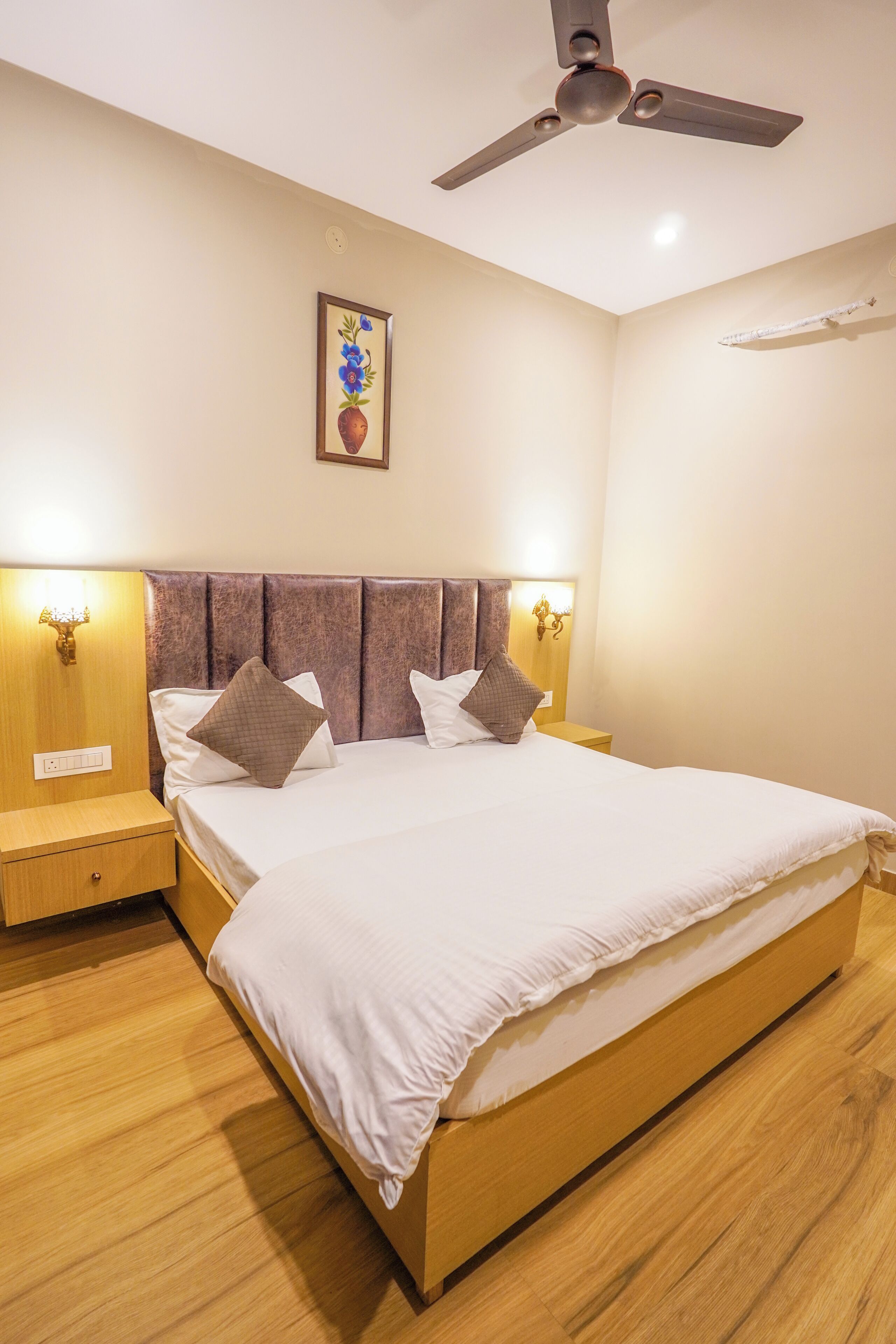 A bedroom with a bed, wooden headboard, nightstands, wall-mounted lamps, and a ceiling fan.