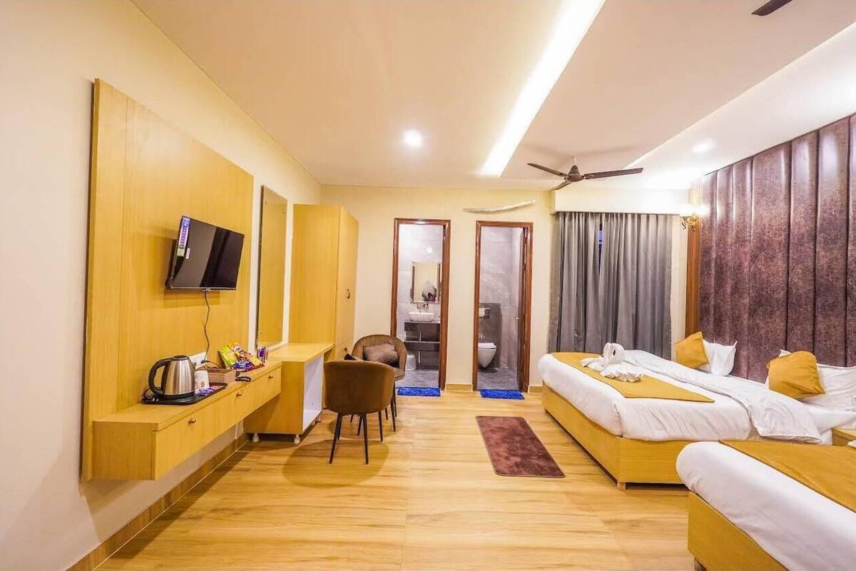 A hotel room with a bed, a desk, a chair, a television, and a ceiling fan.