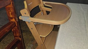 Een eethoek met een houten stoel, een tafel met een grijze tafelkleed, en een grijze bank op de achtergrond.