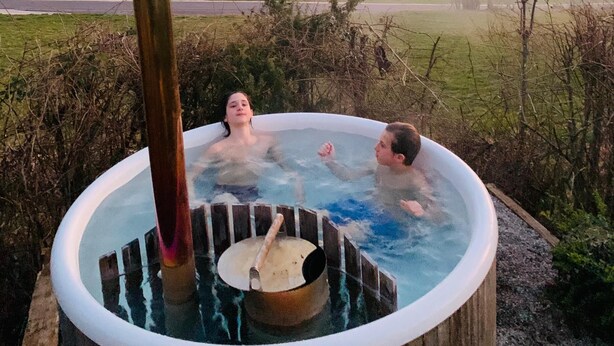 A hot tub with a steam pipe, surrounded by a natural landscape. - Far-reaching views of the Mangfall valley - Quiet house with sauna, hot tub & garden near Munich (Feldkirchen-Westerham)