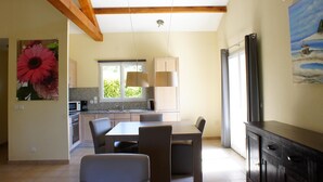 Una cocina amplia con vigas de madera, un comedor con sillas y un cuadro en la pared.