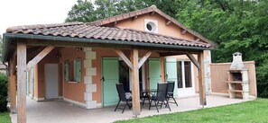 A house with a covered patio, green shutters, and a stone fireplace. - Villa in Parthenay With Private Garden (Les Forges)