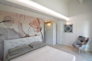 A bedroom with a bed, a chair, a wardrobe, and a wall with a large abstract painting. - Spacious Stay in Montelupone (Montelupone)
