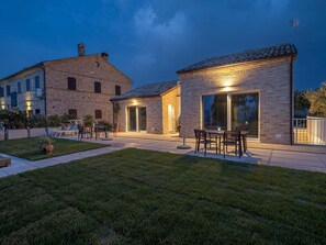 A two-story building with a brick facade, a patio with outdoor furniture, and a large sliding glass door. - Spacious Stay in Montelupone (Montelupone)