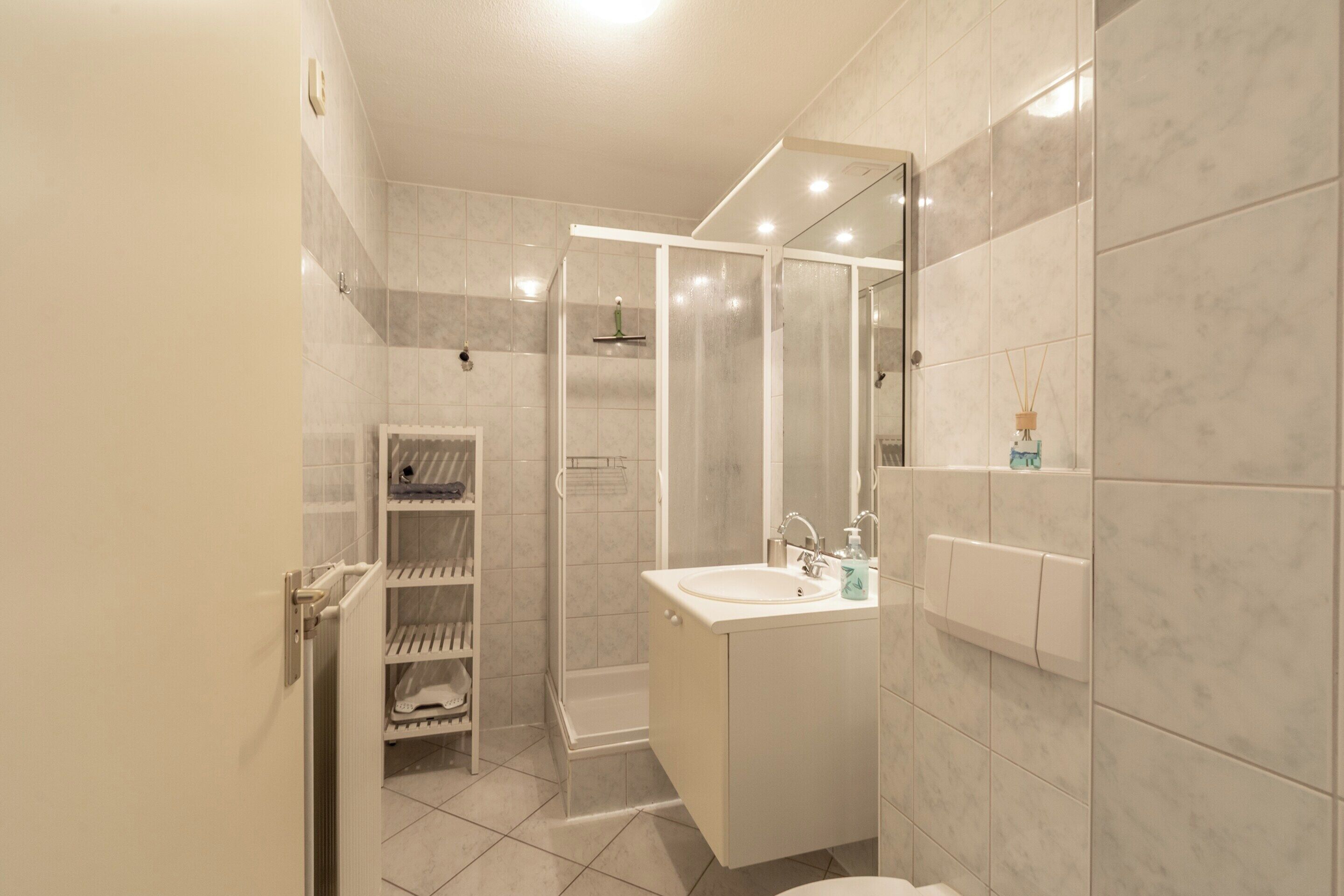 Ein modernes Badezimmer mit Dusche, Toilette, Waschbecken und einer Duschkabine aus Glas.