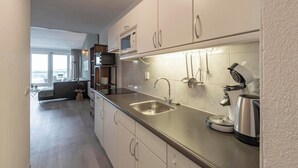 Una cucina moderna con lavello in acciaio inossidabile, forno a microonde integrato e macchina per il caffè.