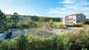 A residential area with a multi-story building, a parking lot, and surrounding greenery. - Cozy Dune-view Apartment (Julianadorp)
