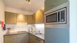 A modern kitchen with stainless steel appliances, a built-in microwave, and a gas stove. - Cozy Dune-view Apartment (Julianadorp)