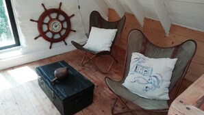 A cozy attic room with a wooden floor, a ship's wheel wall decoration, two rocking chairs, and a black storage box. - Brittany Escape With Garden (Cleden-Cap-Sizun)