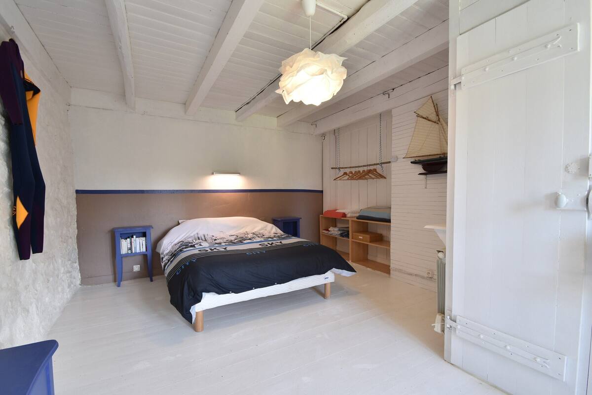 A bedroom with a bed, a hanging light fixture, a radiator, and a wardrobe.