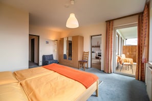 Ein Schlafzimmer mit Bett, Schrank, Stuhl und Blick auf einen Außenbereich.