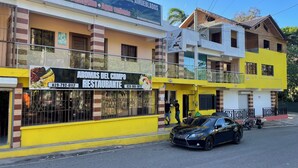 A building with a sign for a restaurant named 'AROMAS DEL CAMPO RESTAURANTE' and a sign above it advertising various amenities like TV, internet, and water. - Aromas de campo hotel (Inoa)