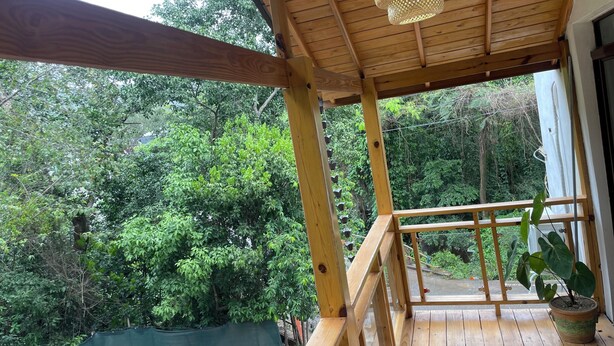 A wooden deck with a railing, a hanging light fixture, and a potted plant. - Aromas de campo hotel (Inoa)