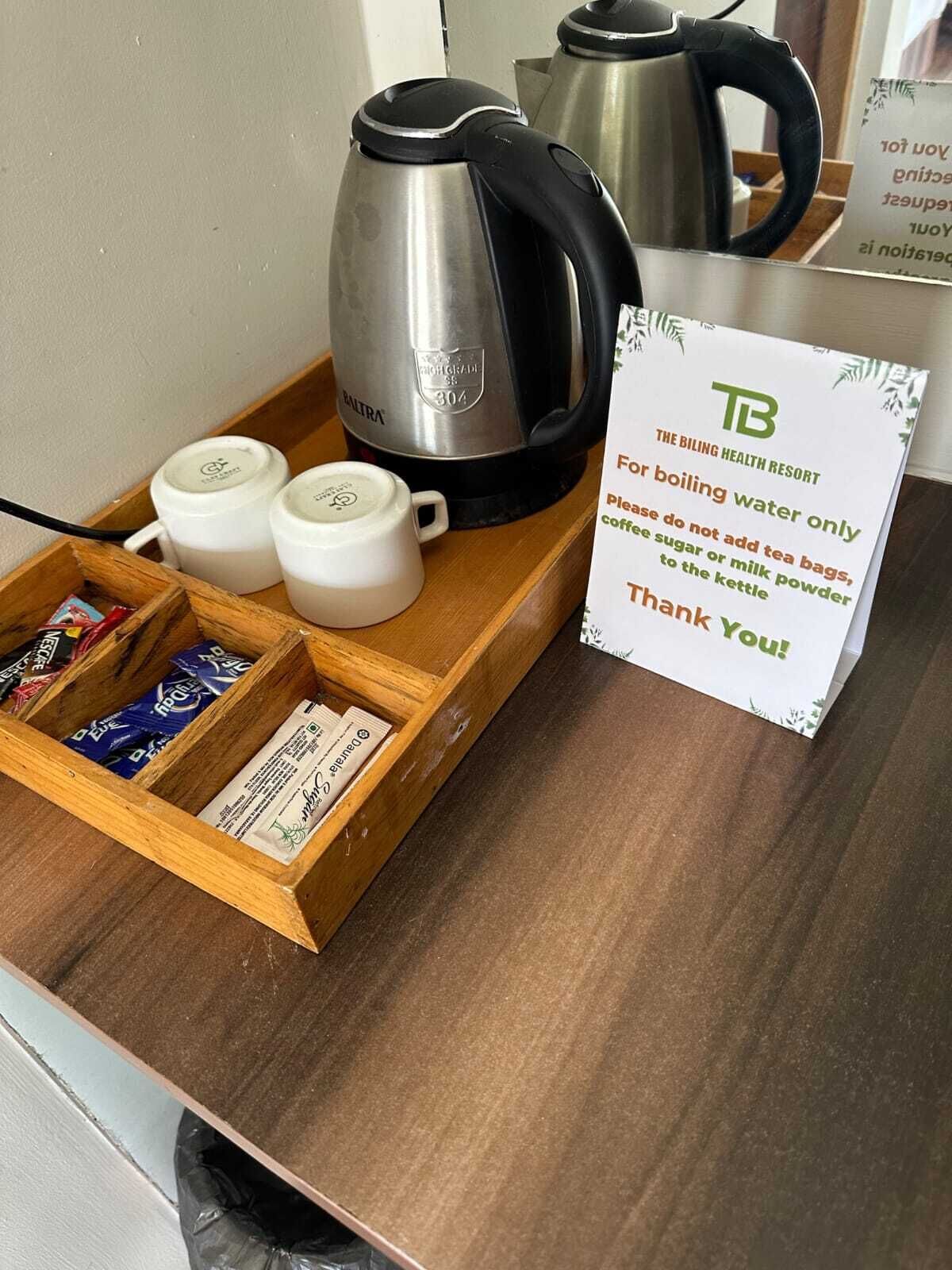 A tray with a kettle, two mugs, and a box of tea bags.