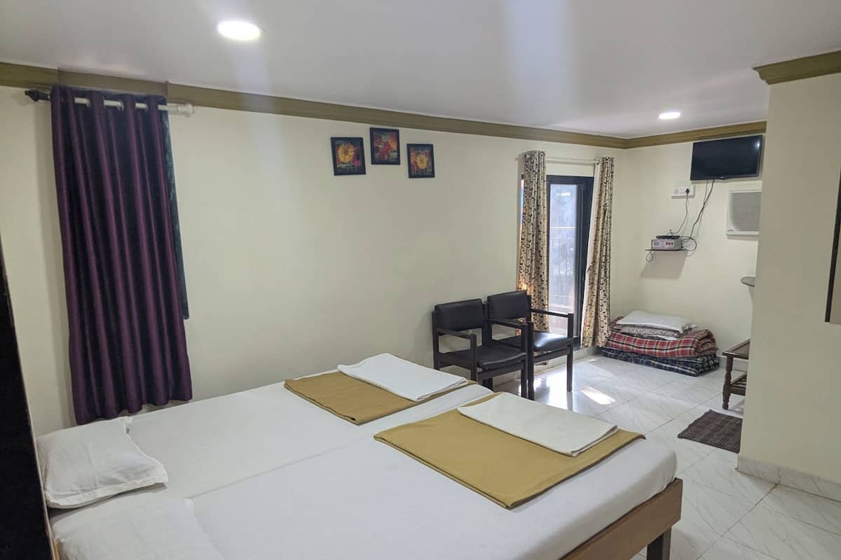 Una habitación de hotel con dos camas, televisión, escritorio y una silla.