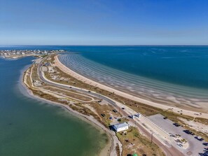 Luftaufnahme einer Küstenlandschaft mit einer gewundenen Straße, einem Strand und einem kleinen Gebäude mit Parkplatz.