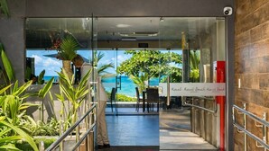 A hotel entrance with a glass door leading to a terrace with a view of the ocean. - Kauai Praia dos Carneiros |Apartamento Pé na Areia (Tamandaré)