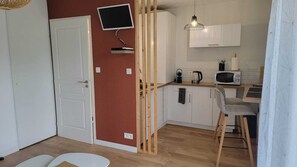 A compact kitchen with a microwave, kettle, and a small dining area with a chair. - Studio 150 m from the beach terrace and private parking (Crozon)