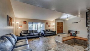 Ein geräumiges Wohnzimmer mit Kamin, Ledersofas und einem Steinkaminumbau.