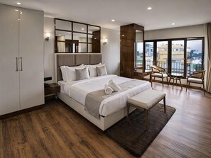 Un dormitorio de hotel moderno con una cama grande, un escritorio y un balcón con sillas.
