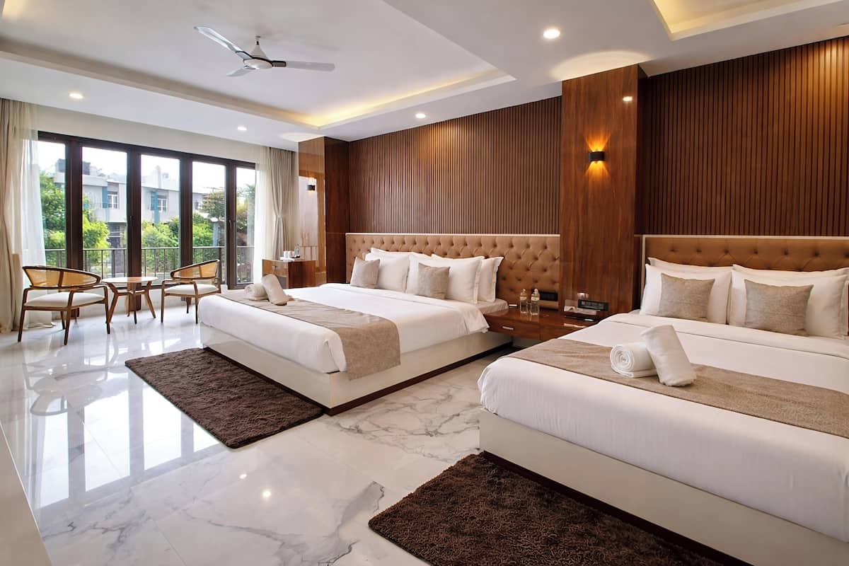 A hotel room with two beds, a balcony, a ceiling fan, and a large window.