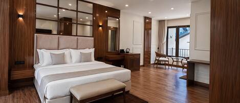 A modern hotel room with a large bed, a desk, and a view of the outdoors.