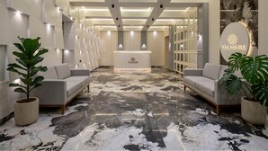A hotel reception area with a marble floor, modern reception desk, and seating. - Valmere Chery Blossom Suites (Shillong)