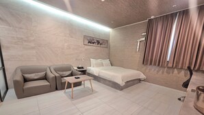 A modern hotel room with a sofa, a bed, a small table, and a painting on the wall. - Suwon Station Hotel Terry's (Suwon)