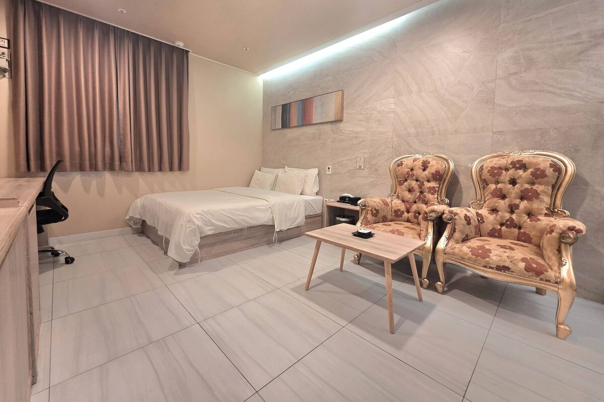 Una habitació d'hotel amb un llit, una escriptori, una cadira i una taula petita.