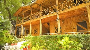 A wooden building with a balcony, surrounded by greenery. - First Impression (Varanasi)