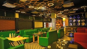 A restaurant with green seating, hexagonal ceiling lights, and a patterned floor. - First Impression (Varanasi)