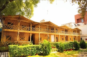 A wooden building with a balcony, surrounded by greenery. - First Impression (Varanasi)