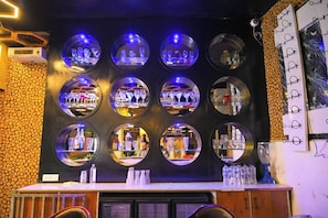 A bar area with circular mirrors, a wooden wall, and a counter with bottles and glasses. - First Impression (Varanasi)