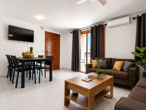 A modern living room with a dining area, a sofa set, a coffee table, and a flat-screen TV mounted on the wall. - Torreblanca near the sea (Torrevieja)