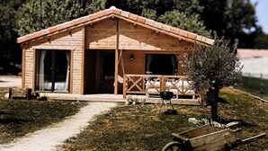 Eine Holzhütte mit Veranda, einem kleinen Tisch und einem Grill.
