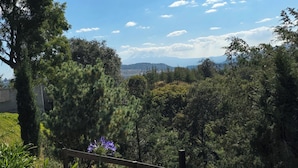 A view of a mountainous landscape with a wooden fence in the foreground.