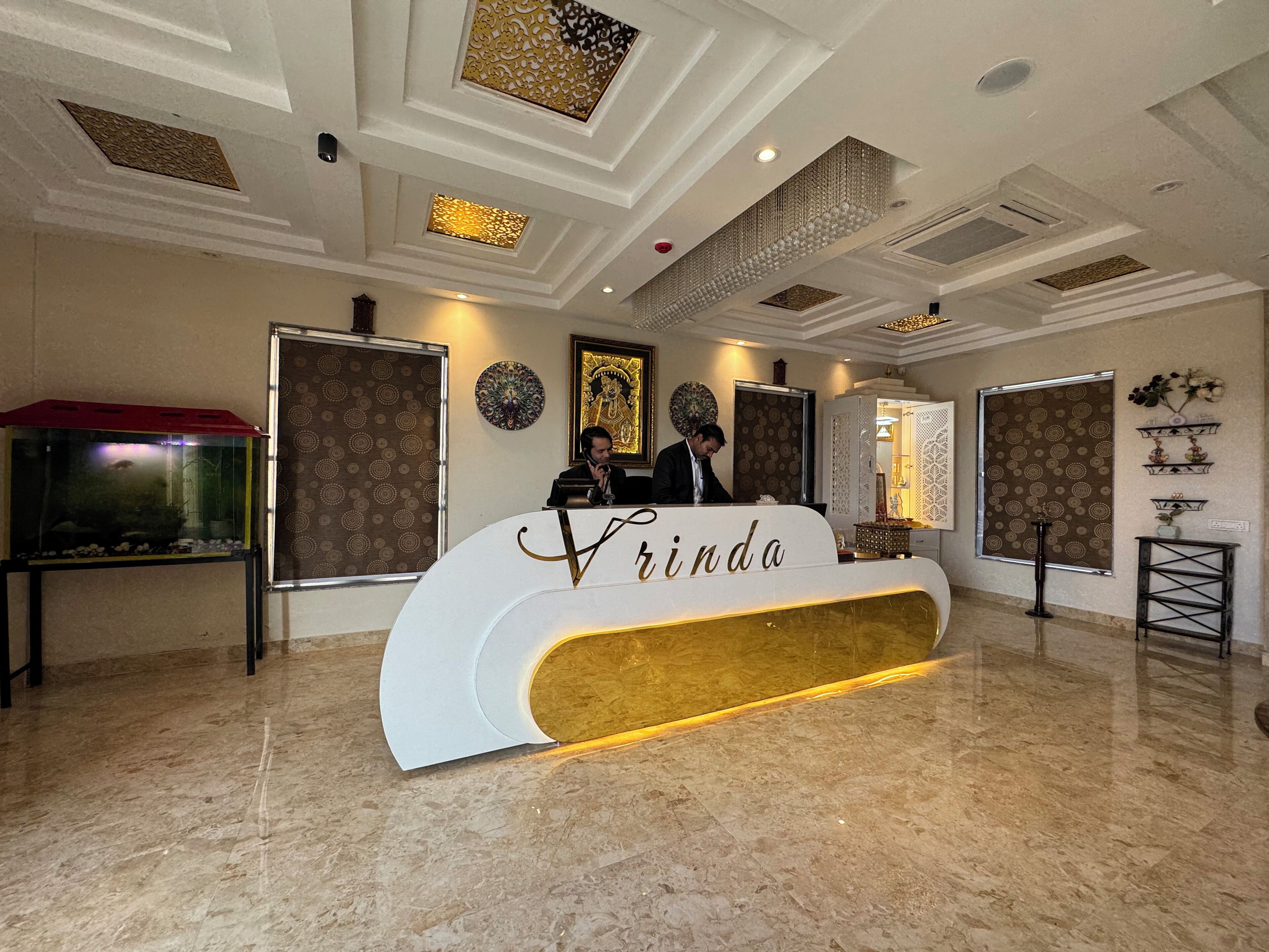 Una recepción con detalles dorados, un acuario, paredes con diseño y un techo con iluminación empotrada.
