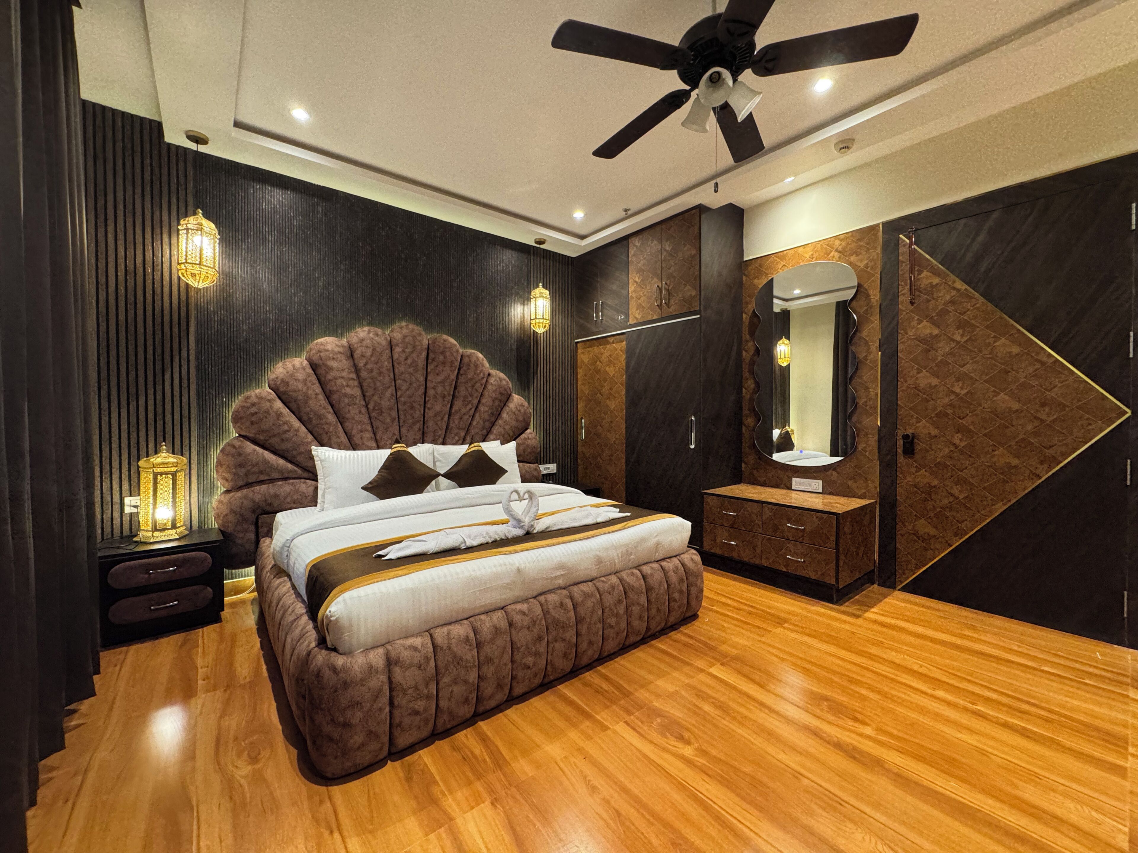 Un dormitorio moderno con una cama grande, un ventilador de techo, una mesita de noche, un aparador y un espejo.
