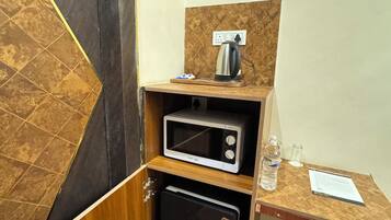 Une petite cuisine équipée d’un four à micro-ondes, d’une bouilloire et d’un petit réfrigérateur.