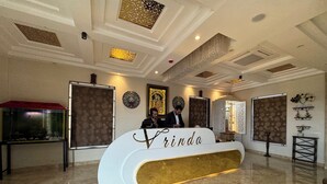 A reception desk with the name 'Frinda' in gold lettering, a patterned wall, a decorative ceiling, and a fish tank. - VRINDA HOTELS (Sitapur)